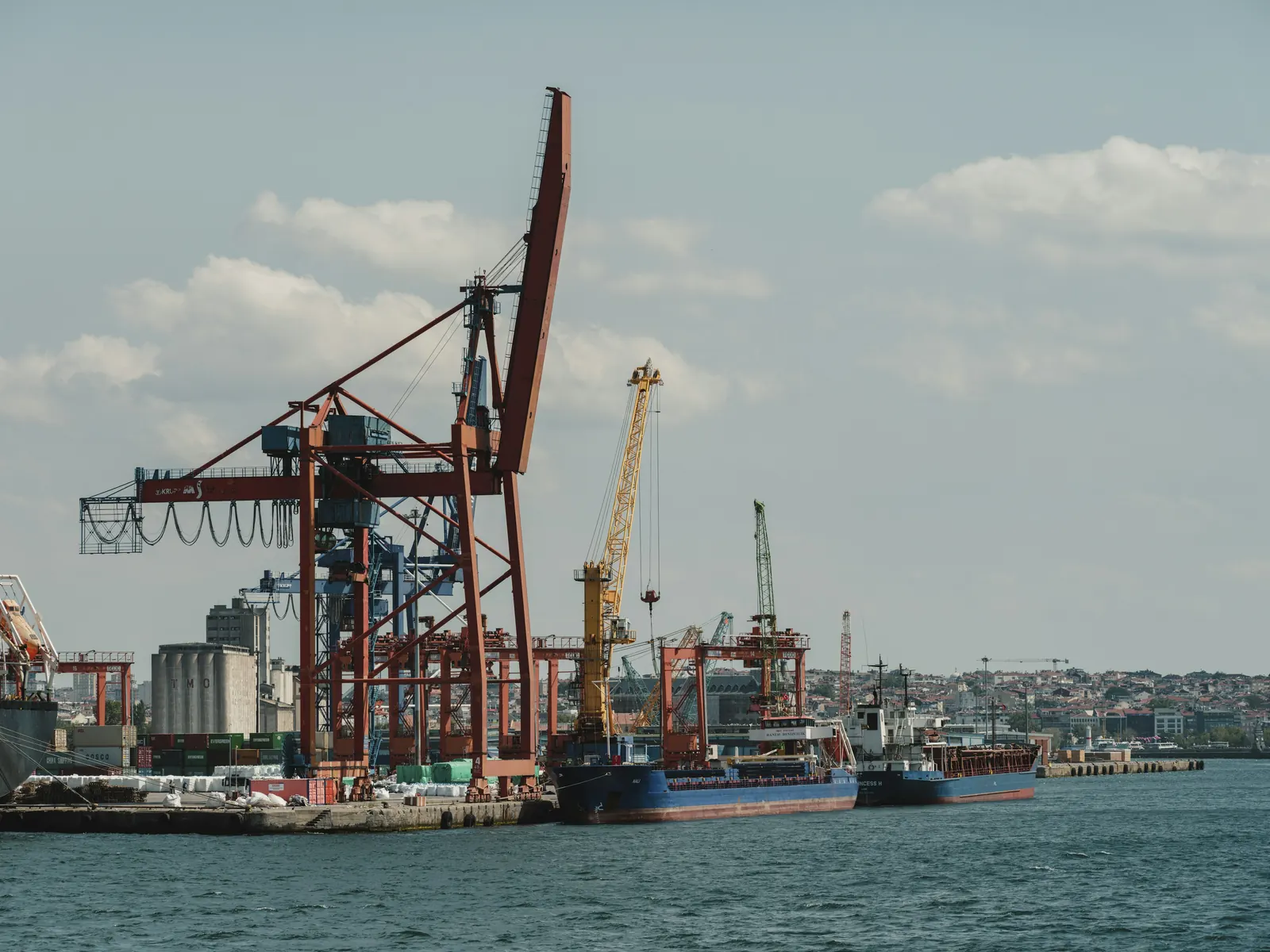 Harbour cranes on a dock under a cloudy sky