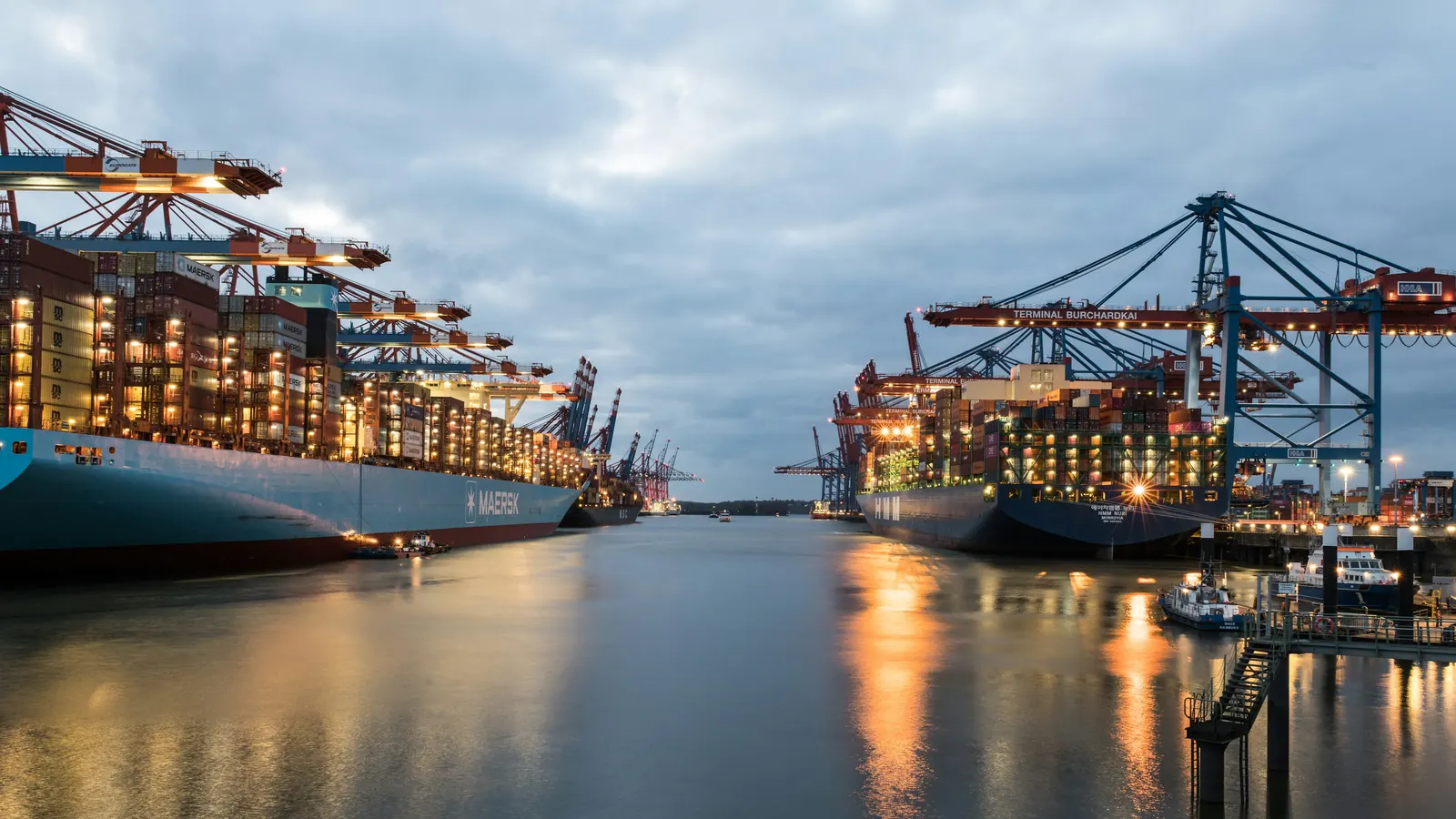 Container ships and lit gantry cranes in the Port of Hamburg at dusk
