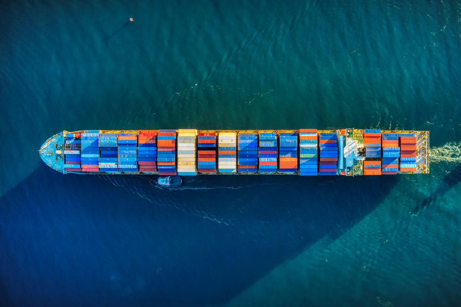 Aerial view of a container ship loaded with colourful containers on deep teal sea