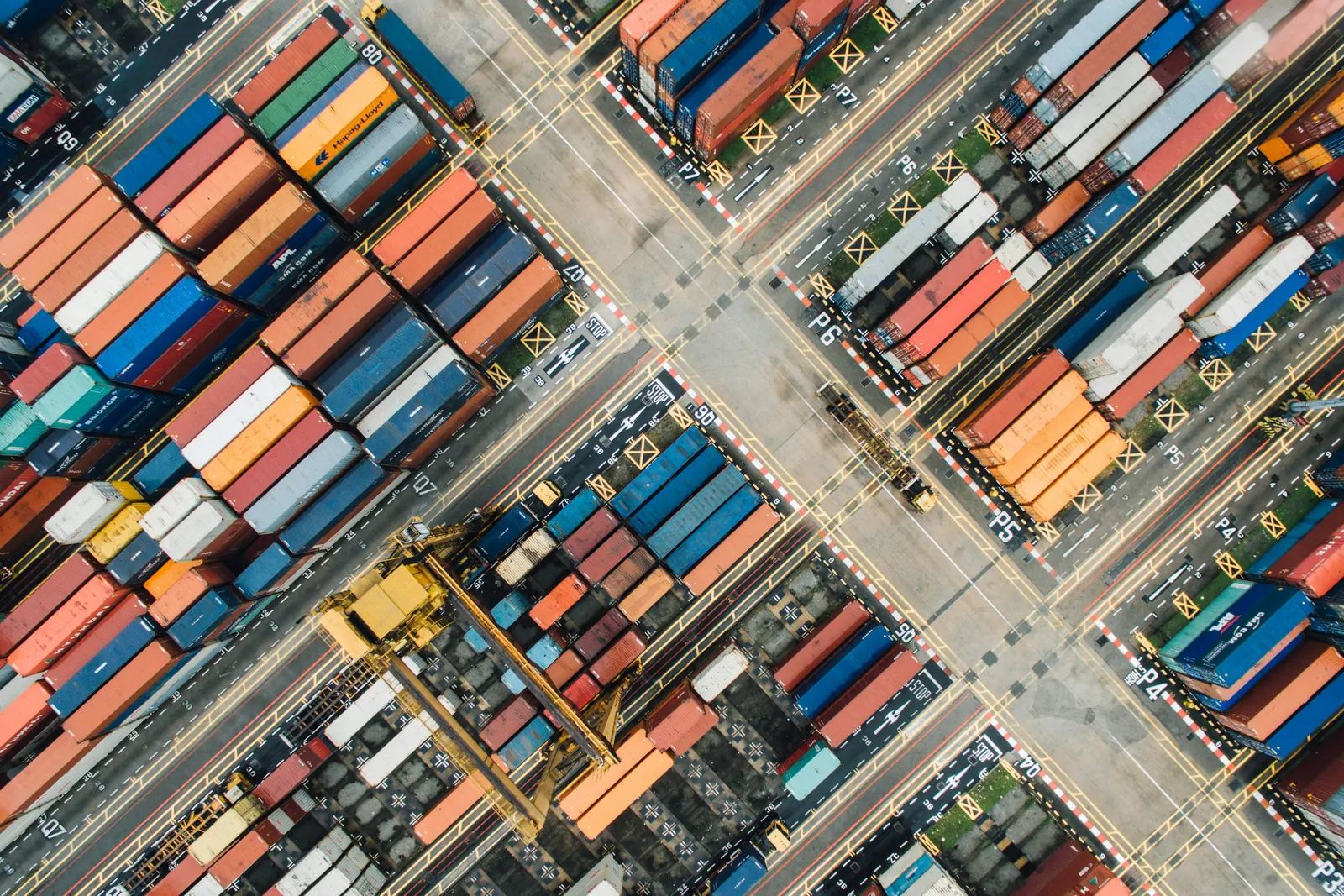 Aerial view of a container terminal: numbered yard blocks of stacked containers, a crane and the roads between them